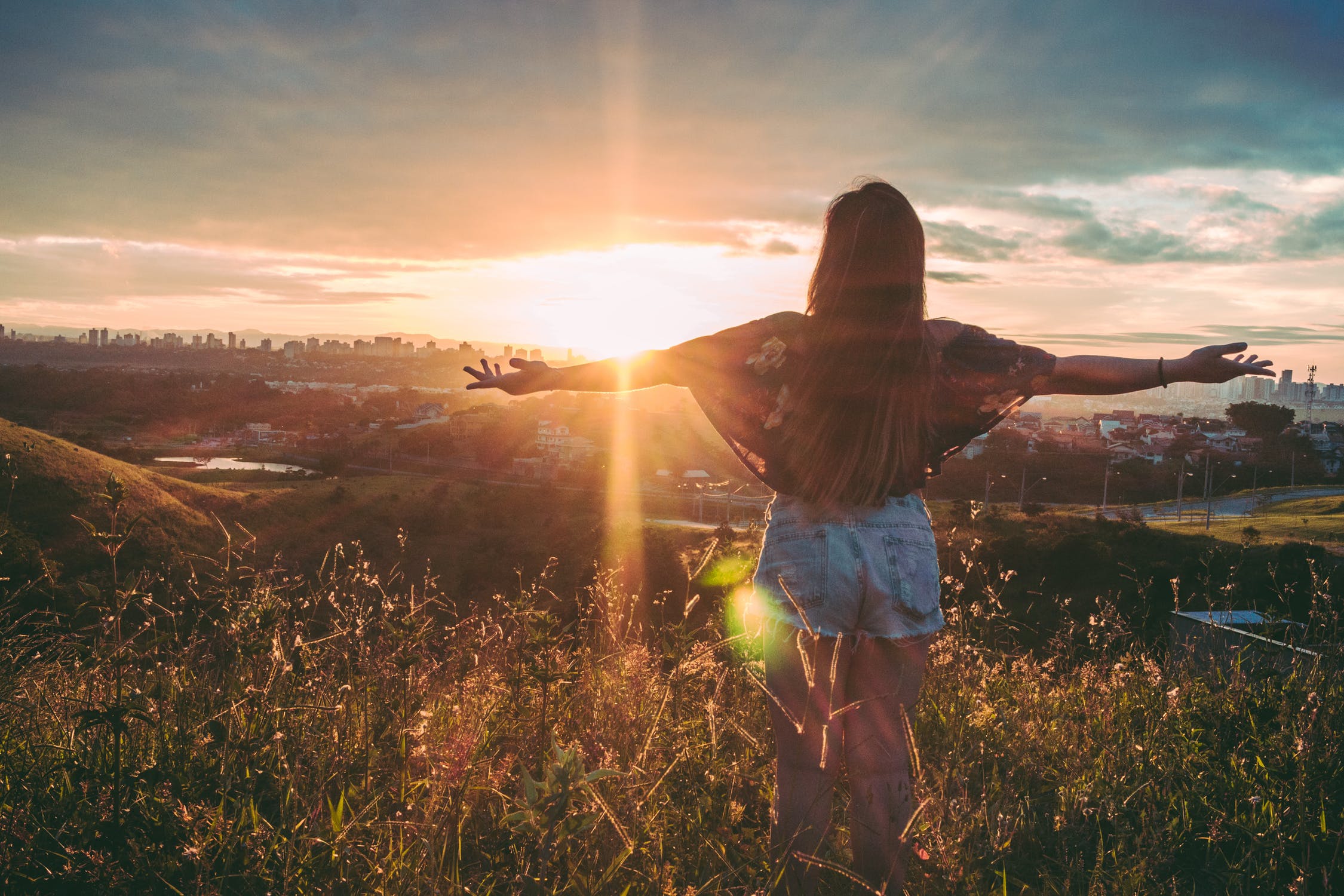 woman standing in field with arms outstretched